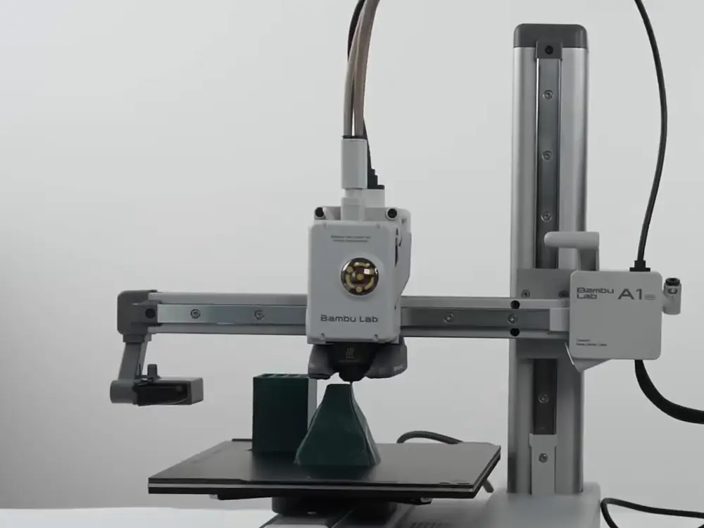 Печатающая голова Bambu Lab A1 mini движется над столом и печатает деталь, кадр ролика производителя