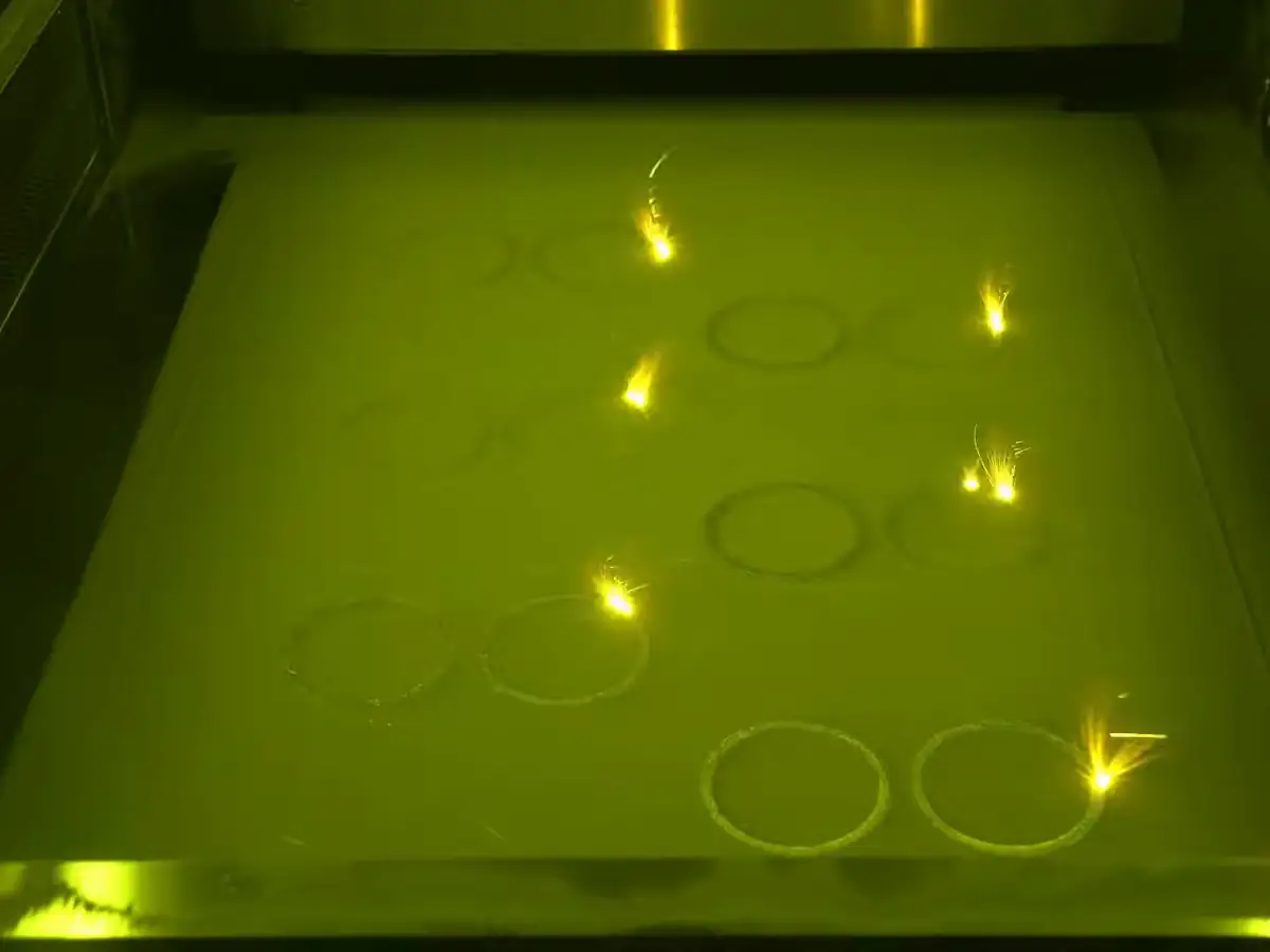 Несколько лазеров одновременно плавят порошок на платформе 3D-принтера HBD, видны искры (анимация)